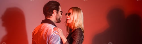 Preview: Stylish woman in sunglasses hugging boyfriend on red background, banner
