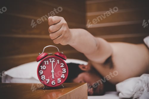Preview: Man being awakened by an alarm clock in his bedroom.
