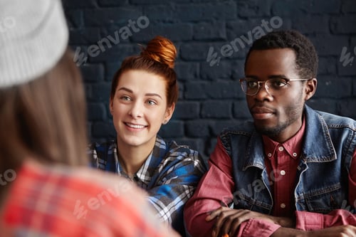 Preview: Beautiful young Caucasian woman with cheerful smile and African male hipster wearing spectacles rela
