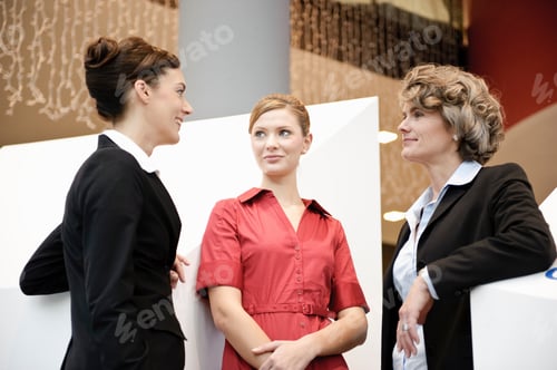 Preview: Three Businesswomen Conversing at Professional Workplace Setting
