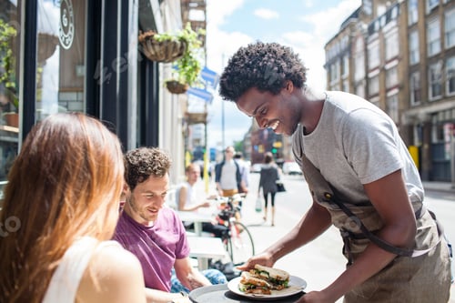 Preview: Waiter serving lunch to couple at city sidewalk cafe