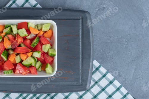 Preview: Shepherd's salad mixed with carrot slices on a navy platter on marble background