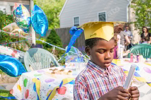 Visualização: Jovem rapaz na formatura do jardim de infância, usando placa de argamassa de papel, portando certificado