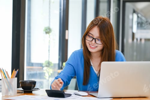 Preview: Woman Working at Desk with Laptop and Calculator