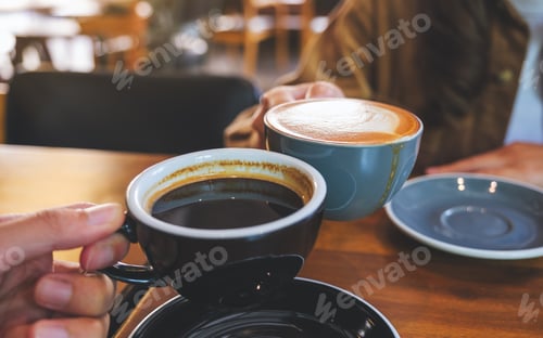 Preview: Closeup image of a couple people clinking coffee cups together in cafe
