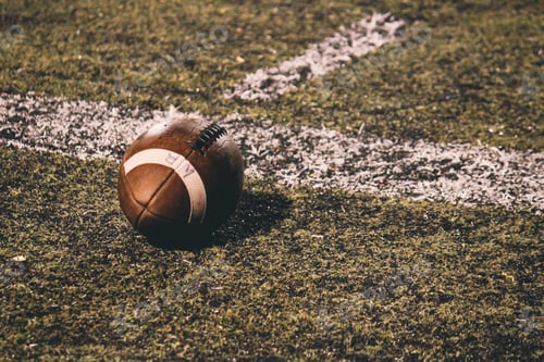 Preview: A football sits on the ground at a Friday night high school football game.