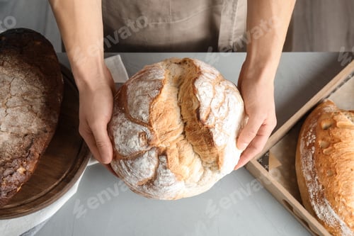 Preview: Baker holding loaf of bread over table, top view