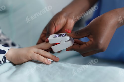 Preview: Close up of pediatric clinic nurse measuring sick child oxygen levels while in patient recovery ward