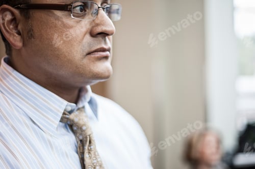 Visualização: Empresário hispânico de camisa e gravata em pé em um espaço de centro de convenções.