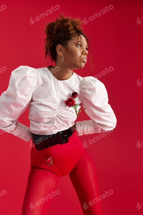 Preview: Stylish young woman posing elegantly in bright red attire against a vibrant backdrop
