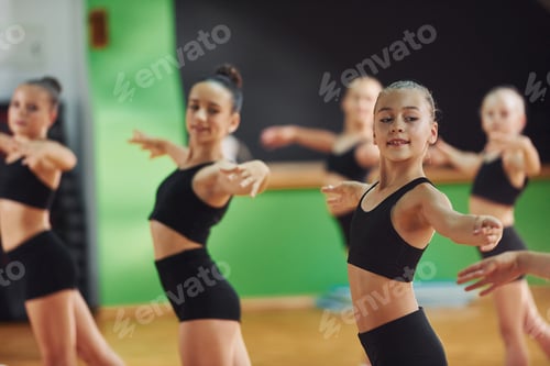 Preview: Group of female kids practicing athletic exercises together indoors