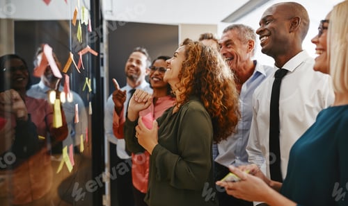 Preview: Smiling businesspeople brainstorming with sticky notes on a glass wall