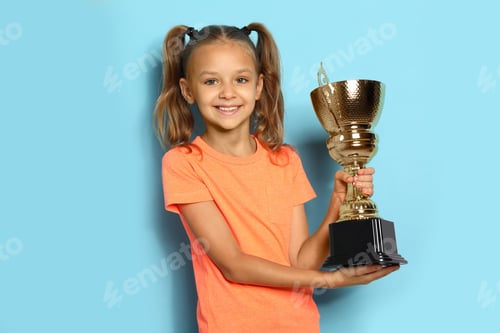 Preview: Happy girl with golden winning cup on blue background