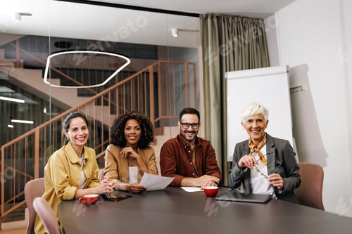 Preview: Portrait of four business colleagues, smiling for the camera, sitting at the office.