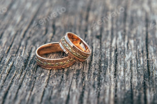 Preview: Wedding rings in hands of bride on wood background