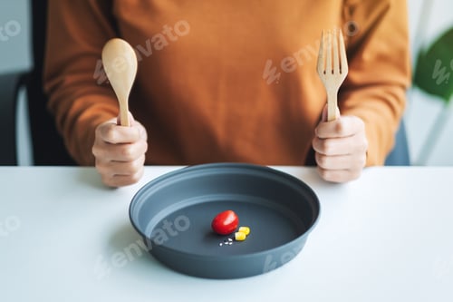 Preview: Closeup image of a woman holding spoon and fork to eat small amount of food for diet concept
