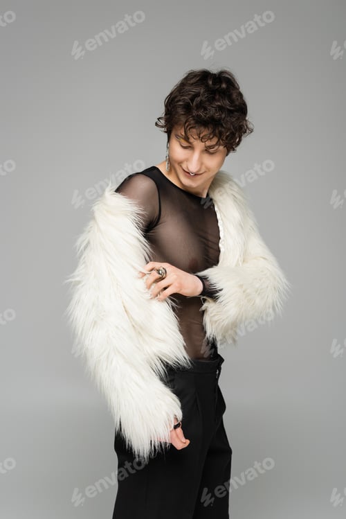 Preview: brunette nonbinary person wearing white faux fur jacket isolated on grey