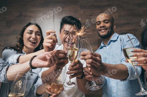 Visualização: Jovens alegres segurando taças de champanhe e faíscas acesas em ambientes fechados