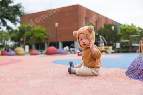Preview: Baby sitting on grass wearing cute bear hat