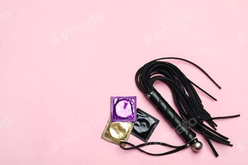 Preview: Whip and condoms on pink background, top view with space for text. Sex game