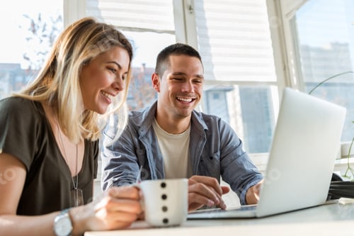 Preview: Smiling young couple looking at laptop