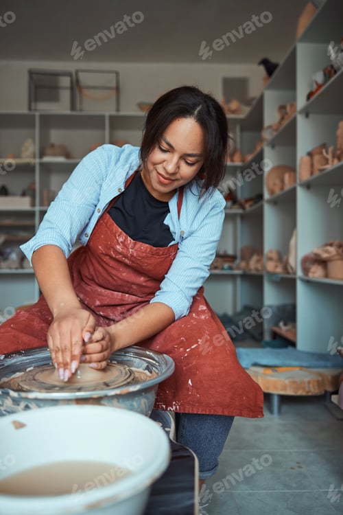 Preview: Charming young woman throwing clay pot on pottery wheel