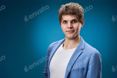 Preview: young guy looking at the camera on blue studio background