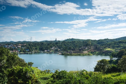 Preview: Scenery of Mon village on riverside and big buddha statue on hill in tropical rainforest on dam