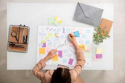 Preview: Overview of brunette businesswoman making working notes on sticky notepapers