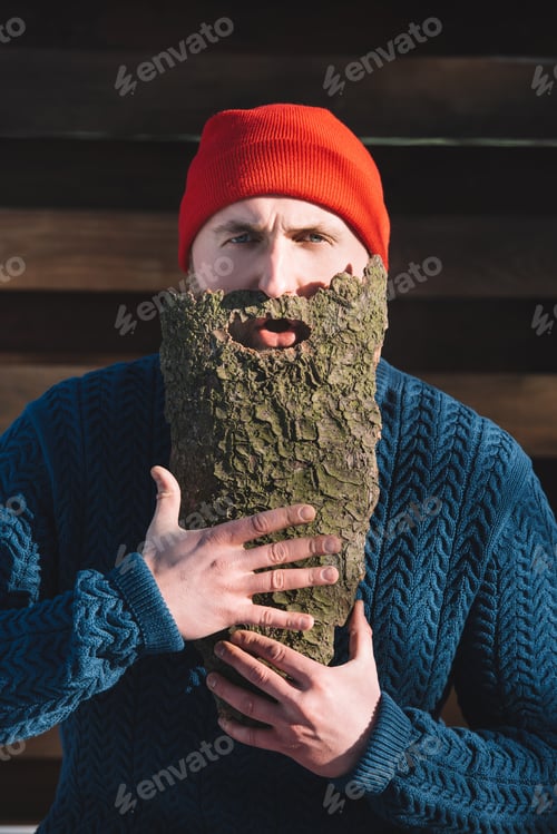 Preview: portrait of man with beard made of wood bark looking at camera outdoors