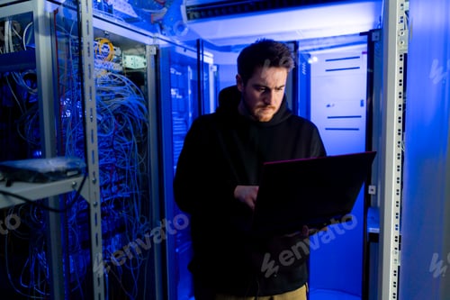 Preview: focused hacker in data center hacking software system vulnerable cyber security server room
