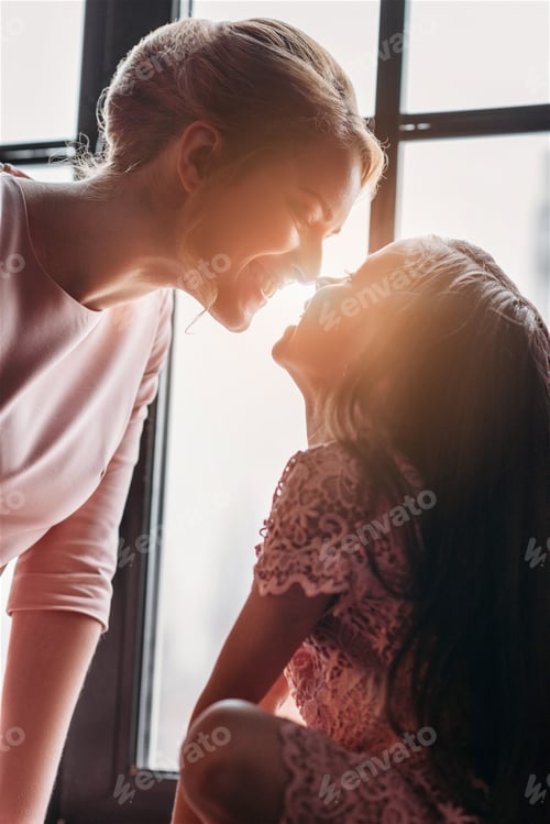 Preview: mother and daughter cuddling on sunshine background
