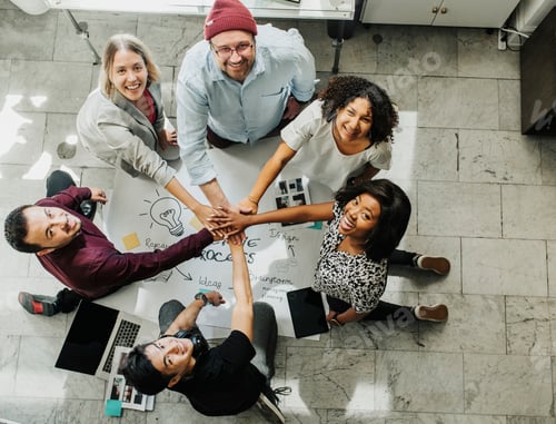 Preview: Happy team stacking hands on a creative ideas chart