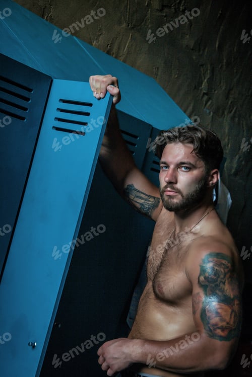 Preview: Strong Man in a Blue Locker, Expressing Confidence in a Rustic Indoor Setting