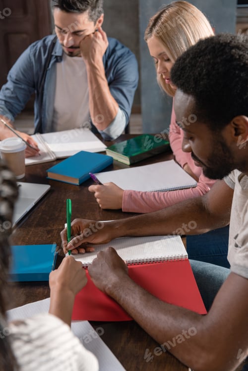 Preview: multiethnic students studying and writing in copybooks at home