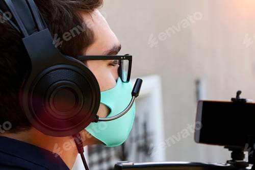 Preview: Closeup photography of videographer working outdoor.Face mask as protection from covid on the face.