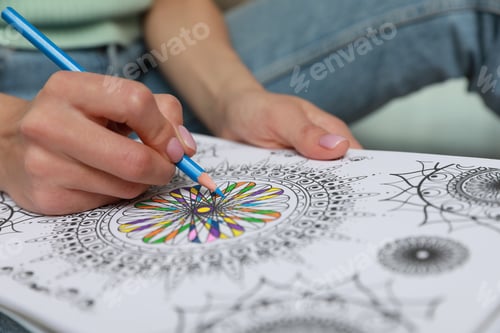 Preview: Young woman coloring antistress page on blurred background, closeup