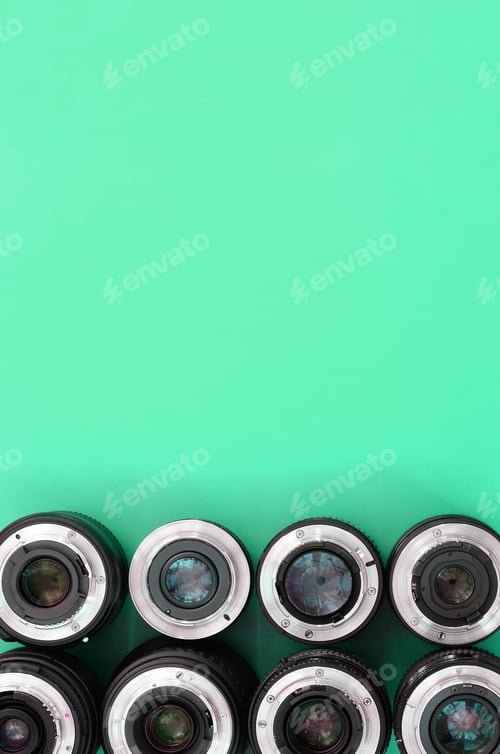 Preview: Several photographic lenses lie on a bright turquoise background. Copy space