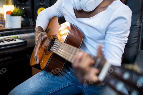 Preview: Acoustic guitar held by musician of African ethnicity during process of singing