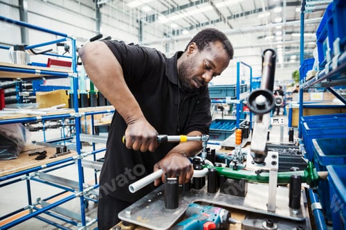 Preview: Male skilled factory worker, a man holding a tool, working to assemble parts of a bicycle in a