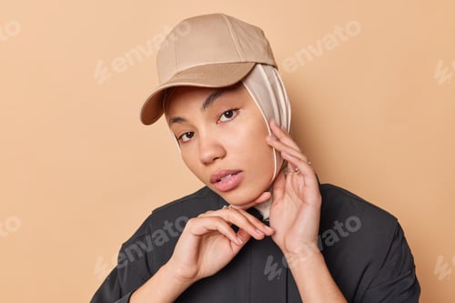 Preview: Portrait of serious Islamic woman touches face gently looks directly at camera has no makeup healthy