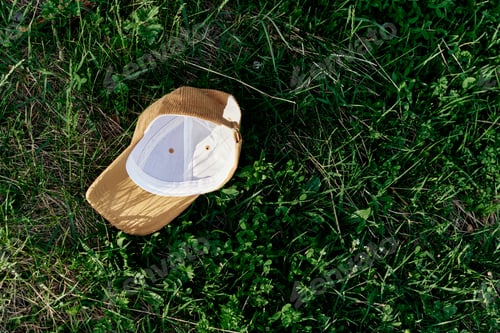 Preview: A yellow sports cap lies upside down on the green grass. Spring outdoor sports games