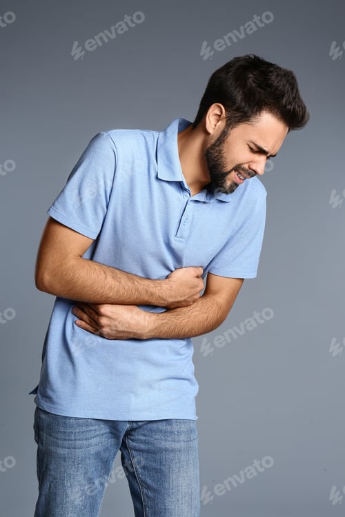 Preview: Man suffering from stomach pain on grey background