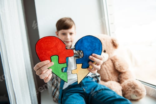 Preview: A cute boy holds a puzzle in the form of a heart. World autism awareness day, Mental health care