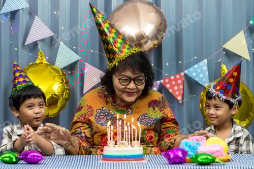 Preview: Celebrating they birthday, blowing candles on homemade baked cake, indoor.