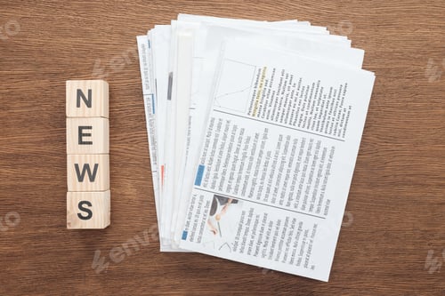 Preview: top view of wooden cubes with word news and newspapers on wooden tabletop