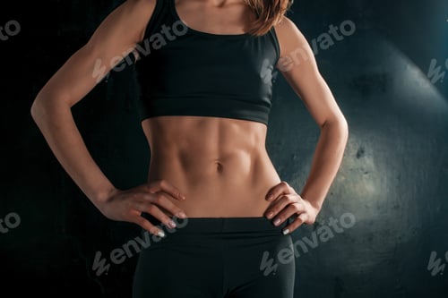 Preview: Muscular young woman athlete on black