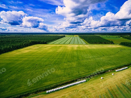 Preview: Aerial view of Tractor mowing green field in Finland.