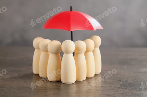 Preview: Human figures under umbrella on grey table. Insurance concept