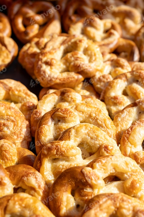 Preview: Crispy pretzels covered with melted cheese glow in warm sunlight, creating rich texture